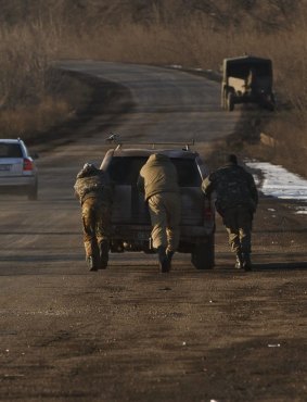 Ukrainian troops push a car  outside Artemivsk, Ukraine, while pulling out of Debaltseve.