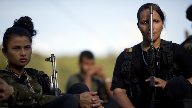 Juliana, 20 (left), and Mariana, 24, soldiers for the Revolutionary Armed Forces of Colombia, listen to a commander speak on the peace negotiations in June.