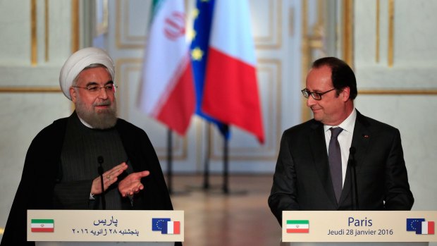 Iranian President Hassan Rouhani, left, applaudes France's President Francois Hollande, at a press conference at the Elysee Palace in Paris on Thursday.