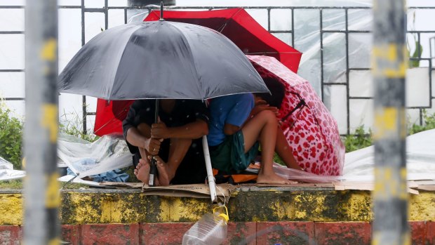 Residents huddle together under their umbrellas as strong winds and rain are brought by Typhoon Koppu.