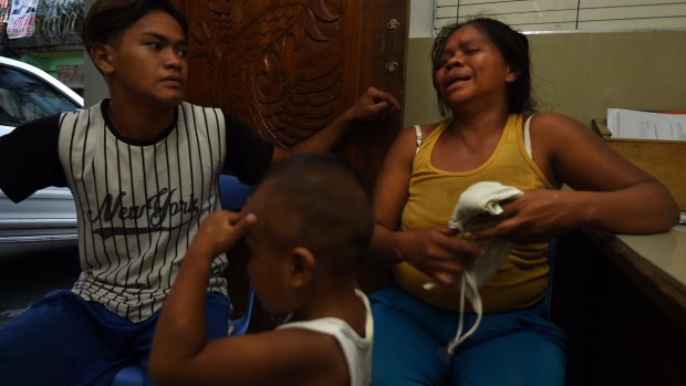 A neighbour comforts Ruth-Jane Sombrio at the funeral home where her husband is being held in Binondo District, Manila. 