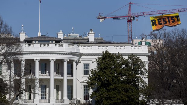Greenpeace activists hang a banner off of a construction crane that reads "Resist" past the White House in Washington, DC.