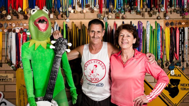 Maria and Jim White with their Canberra Times fun run medals, along with Jims kermit the frog fun run costume. Maria and Jim have been participating in the Canberra Times fun run for 40 years. 