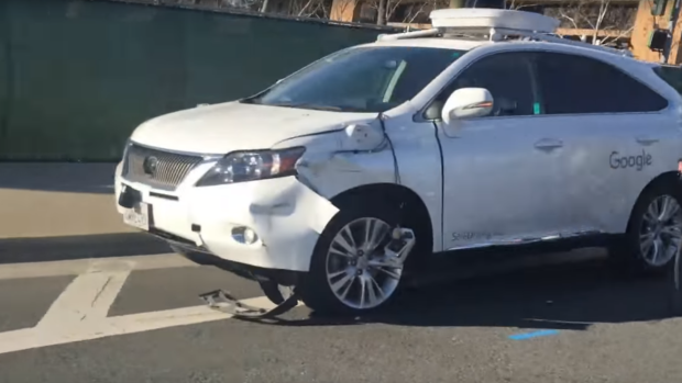 A self-driving car sits damaged on the side of the road after clipping a bus.