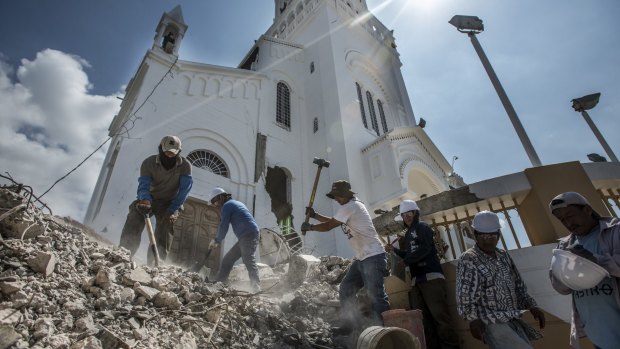 Workers clean up the debris of the steeple of the basilica in Montecristi, Ecuador, left from a recent earthquake.