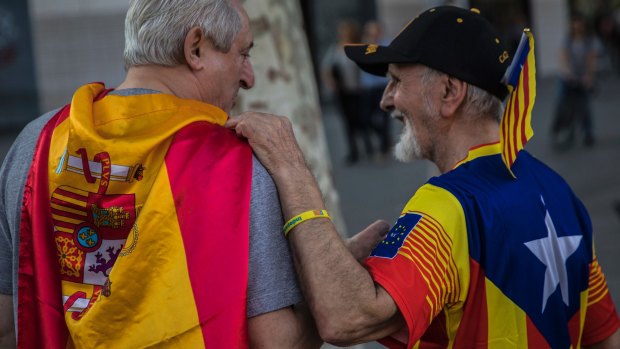 Two men, one wearing a Spanish flag, left, and the other wearing an estelada' or independence flag, talk during Spain's National Day in Barcelona on Thursday.
