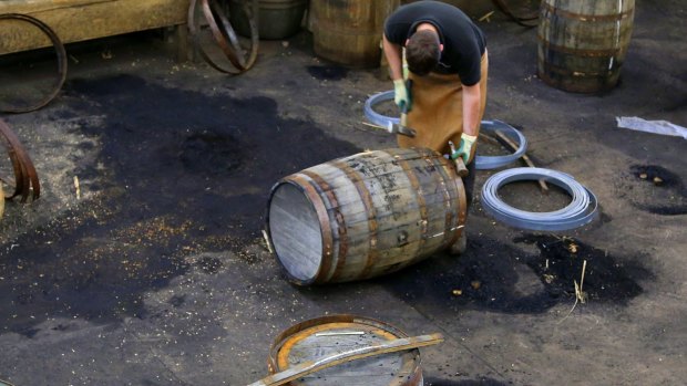 A distillery staff member works on a whisky barrel in Scotland, which has become the first country to set a minimum price on booze.