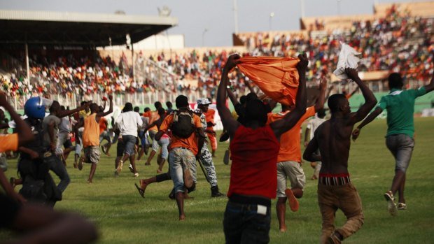 Police chase invading fans on the pitch after Ivory Coast qualified for the African Nations Cup.