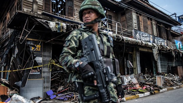 Soldiers on alert at the burnt out bombed remains of a traditional timber shop.