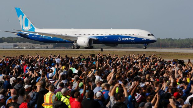 Boeing employees raise up their camera phones to record the first test flight of the new Boeing 787-10 Dreamliner.