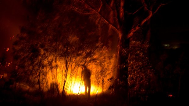 Long, hot summer: Adam Watkin douses spot fires near his home on Three Chain Road near Lancefield in Victoria.