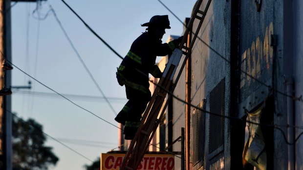 A firefighter climbs a ladder after a deadly fire at a warehouse rave party in Oakland, California.