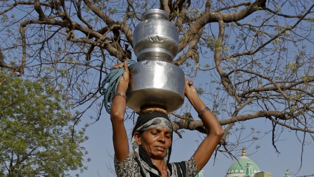 An Indian woman carries pitchers filled with drinking water collected from a well at Gibpura village on the outskirts of Ahmadabad, Gujarat state, India.