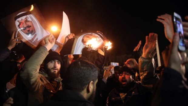 Iranian protesters burn photos of the Saudi royal family on Saturday.