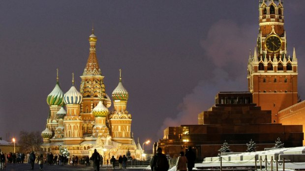 People walk in Red Square, with St. Basil Cathedral, left, the Kremlin's Spassky Tower, right. 
