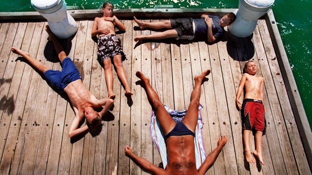 Jay,14, Brad,13, Ben, 9, and Christopher, 9, warm up on Lagoon Pier with a local sun bather. 