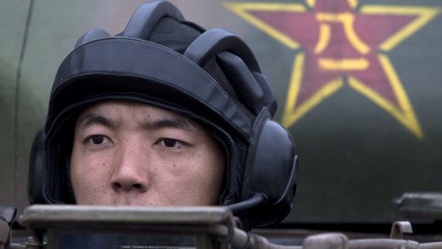A People's Liberation Army cadet rides in a tank.