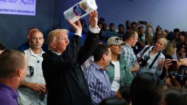 President Donald Trump tosses paper towels into a crowd as he hands out supplies at Calvary Chapel in Guaynabo, Puerto Rico.