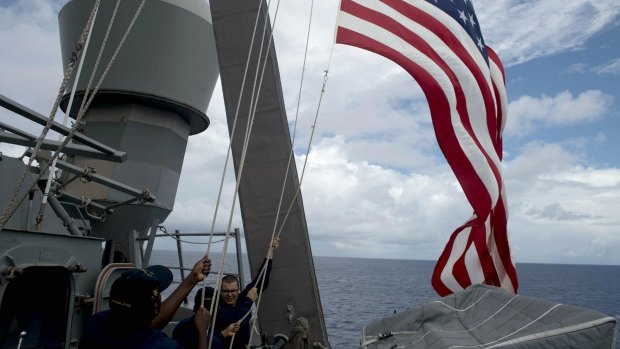 U.S. Navy personnel raise their national flag on the USS John McCain in 2014.