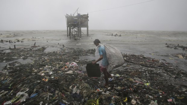 A Filipino man scavenges recyclable materials near a house on stilts as strong winds and rains caused by Typhoon Koppu hit the coastal town of Navotas, north of Manila.