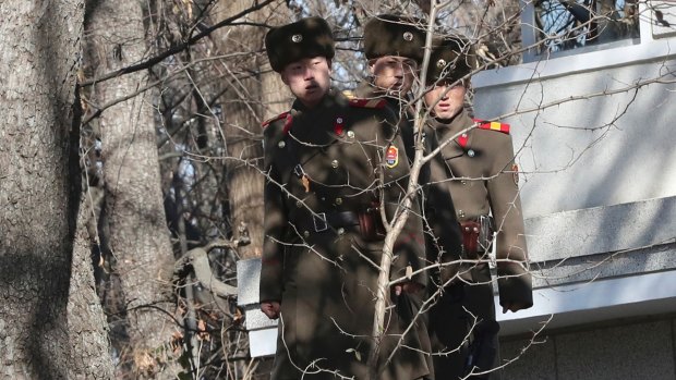Three North Korean soldiers look at the South side near the spot where a North Korean soldier crossed the border on November 13, at the Panmunjom in the Demilitarized Zone, South Korea.