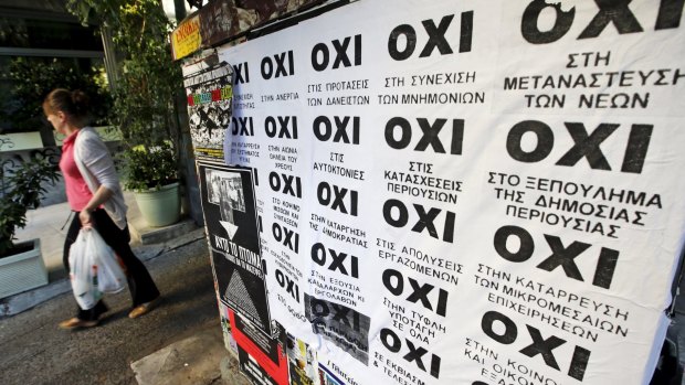A woman walks past referendum campaign posters reading "No" in Greek in Athens.