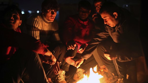 Afghan migrants warm themselves as night falls in the Calais camp.