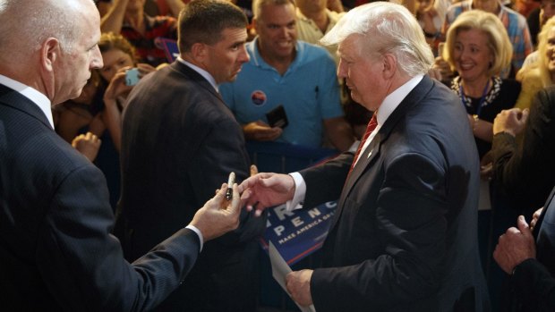 Republican presidential candidate Donald Trump is handed a pen as he signs autographs at a campaign rally in Fayetteville, North Carolina.
