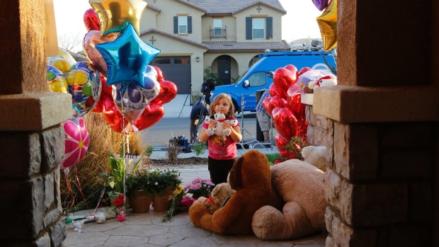 Neighbour Rilee Unger, 3, plays with a toy after dropping off a couple of her own teddy bears on the porch of the Turpin home in Perris, California.