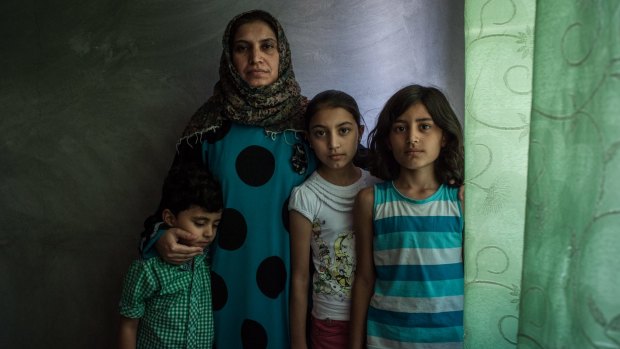 Basma poses for a portrait with her children Nour, Osama and Assadullah in the apartment her family now shares in Sanliurfa, Turkey.