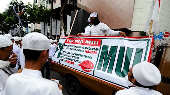 Islamic hardliners rally outside a shopping centre in Surabaya with a sign drawing attention to a fatwa issued by the Majelis Ulema Indonesia (MUI), an Islamic scholarly body, against Muslim staff wearing Christmas hats.