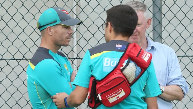 David Warner speaks with medical staff after hurting his neck at training.