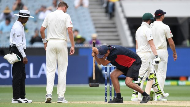 A groundsman takes a sledgehammer to the MCG pitch today. 