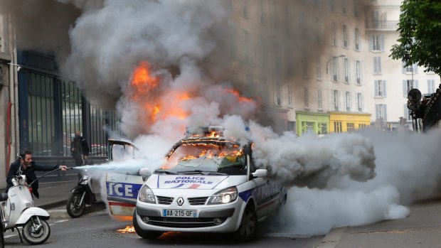 A man tries to put out fire on a burning police car during  protests against a labour reform in May in Paris. 