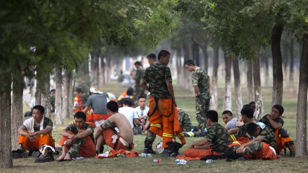 Chinese firefighters rest as they wait to be deployed near the site of the blasts.