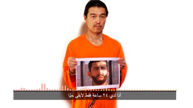 Islamic State hostages: Japanese journalist Kenji Goto holds what appears to be a photo of Jordanian pilot Lieutenant Moaz Kasasbeh in a still photo from a video posted on YouTube on Tuesday. The Arab subtitle reads, "I only have 24 hours left to live".