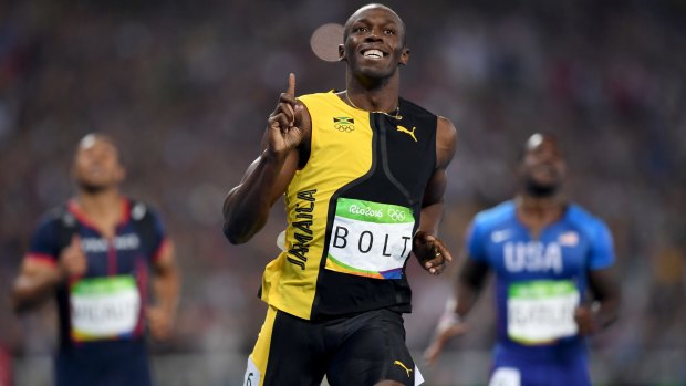 Three-time champion: Usain Bolt celebrates winning the 100m final, with Justin Gatlin, right, finishing second.