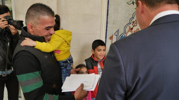 Peter Dutton hands a visa to refugee family member Marwan Alkhdah.