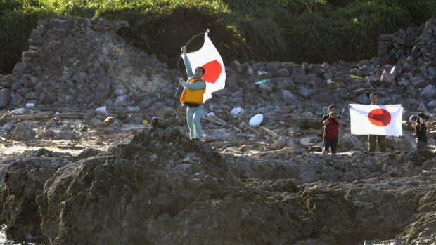Japanese activists hold the national flags on Uotsuri island, one of the islands of Senkaku in Japanese and Diaoyu in Chinese.