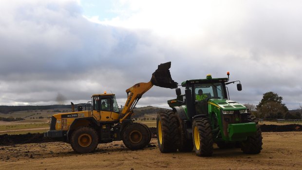 A front end loader moves biosolids to be spread on paddocks on the sheep property Ferndale, NSW. 