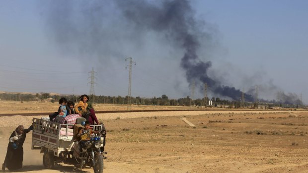 Smoke rises as people flee their homes during clashes between Iraqi security forces and Islamic State group in Hit, 140 kilometres west of Baghdad.