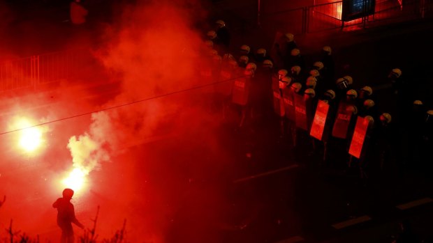 Provocative: A protester taunts the police as several hundred masked men broke away from a far-right march and threw stones and flares at lines of riot police in Warsaw.