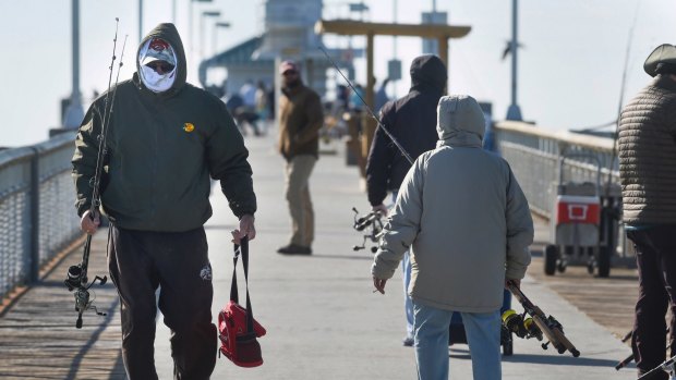 Angler Ron White is bundled up against the cold as he walks down a fishing pier in Fort Walton Beach, Florida.