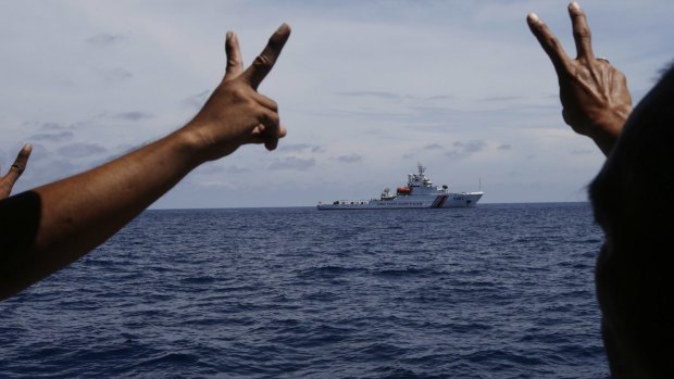Philippine crewmen gesture towards a Chinese ship in the contested area of the South China Sea.