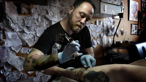 Artist and tattooist artist Leslie Rice applying a vintage-inspired image to Charlie Tapper.