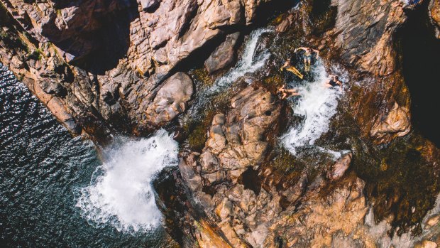 Visitors relaxing in the pristine natural waterfall and plunge pool at Maguk, in the south of Kakadu National Park.