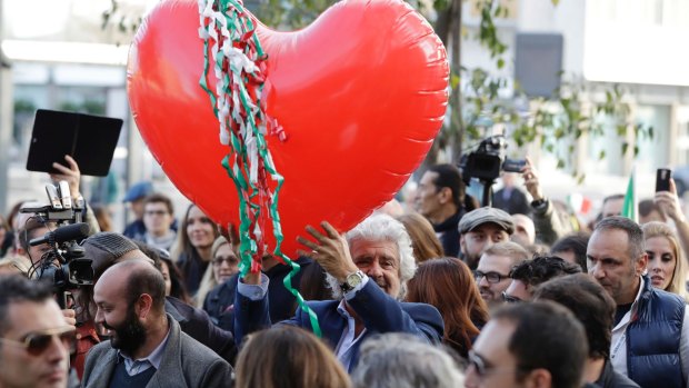 Five Star Movement leader Beppe Grillo holds a heart-shaped balloon adorned with strips in the colours of the Italian flag during a demonstration to support the vote NO in Rome. 
