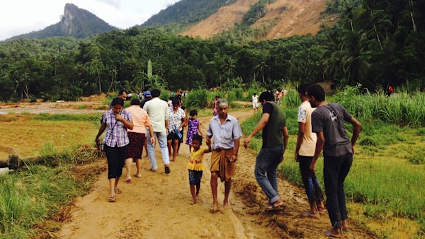 Sri Lankans walk on mud after a massive landslide at Aranayaka in Kegalle District.