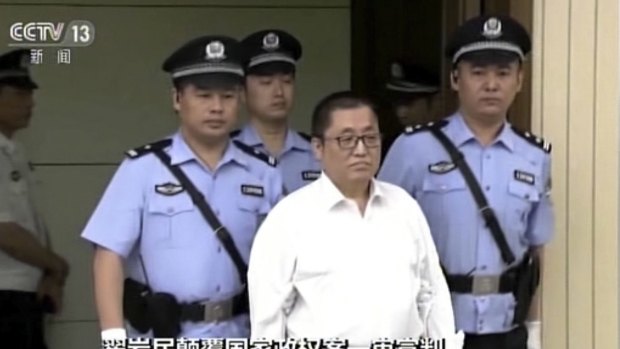 Zhai Yanmin is escorted by policemen as he arrives at the Tianjin court.