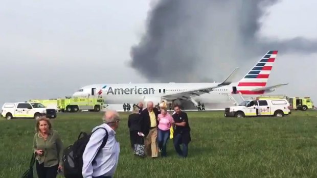 Passengers walk away from the burning American Airlines jet at O'Hare Airport.